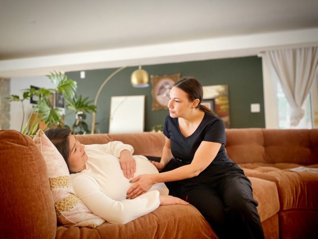 Doula providing comfort and support to a pregnant person on a couch